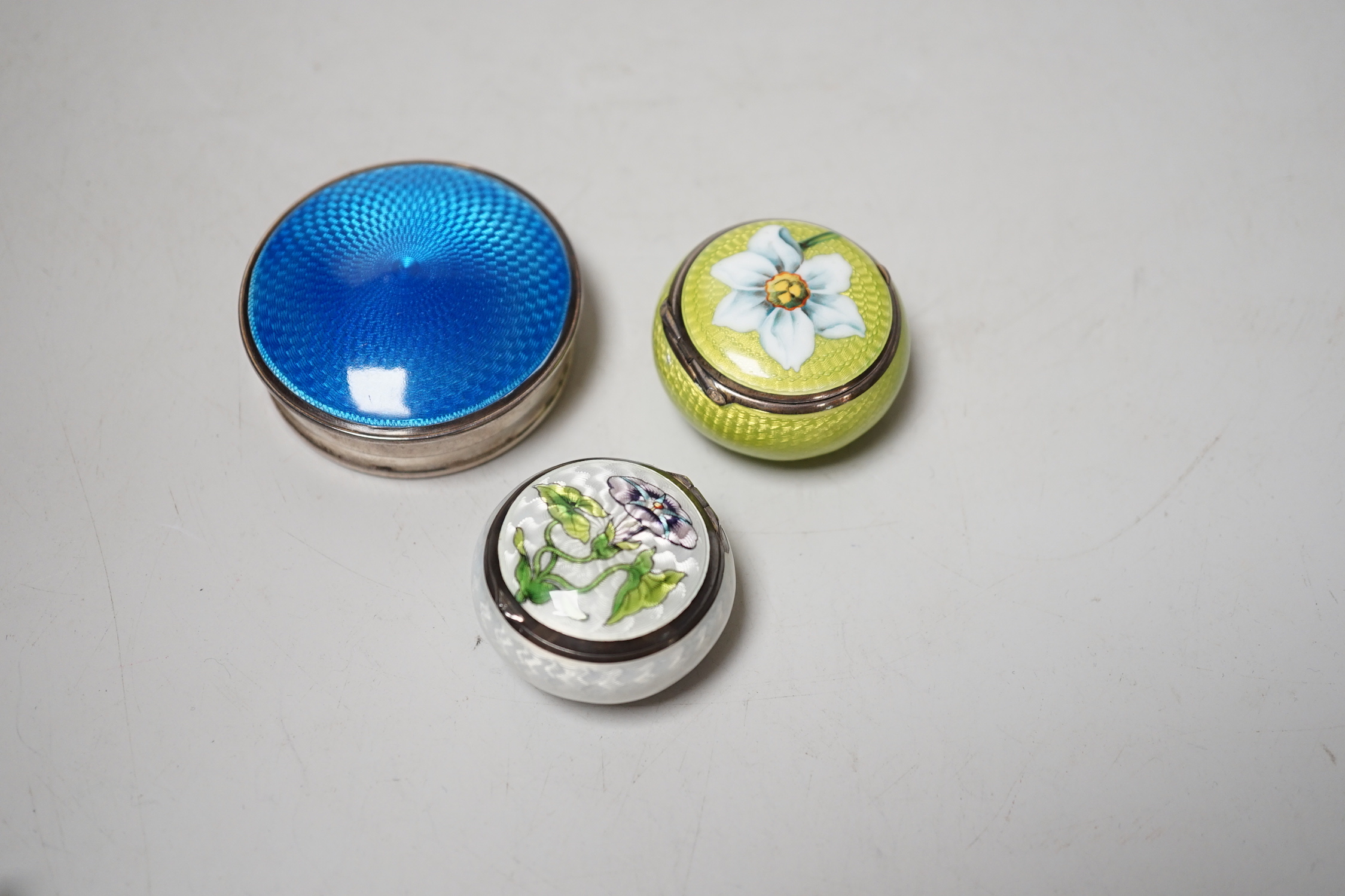 An Edwardian Art Nouveau silver and enamel pill box, import marks for London, 1901, one other 900 standard and enamel pill box and silver and enamel compact, largest 52mm.